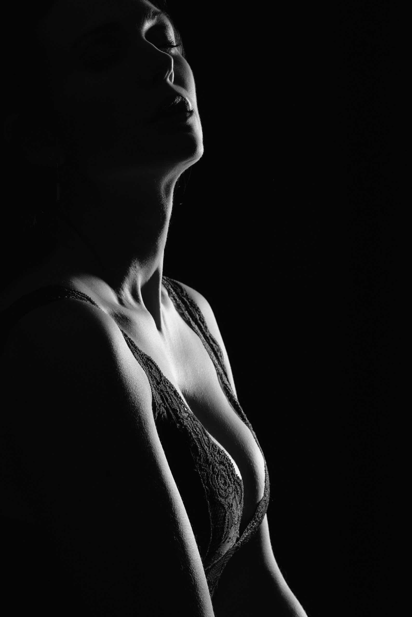 séance photos boudoir femme à Tours par un photographe boudoir photo en noir et blanc ambiance sombre et contrastée qui montre une silhouette de femme en lingerie